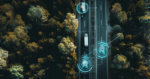 Eine Autobahn aus der Vogelperspektive, Lkws fahren auf der Autobahn und sind mit einem digitalen grünen Kreis gekennzeichnet der das Tracking symbolisiert